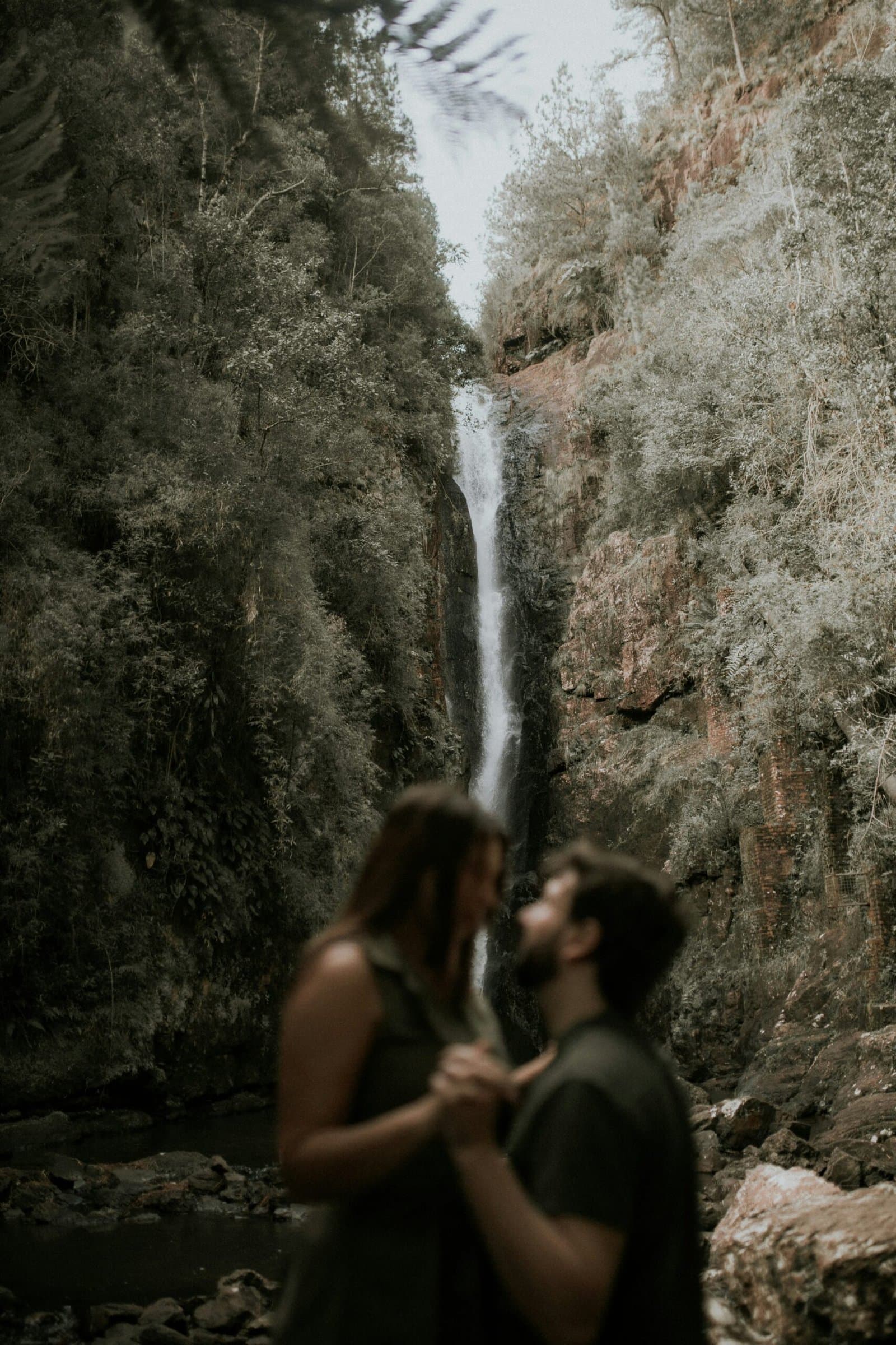 Couple embracing beneath a waterfall